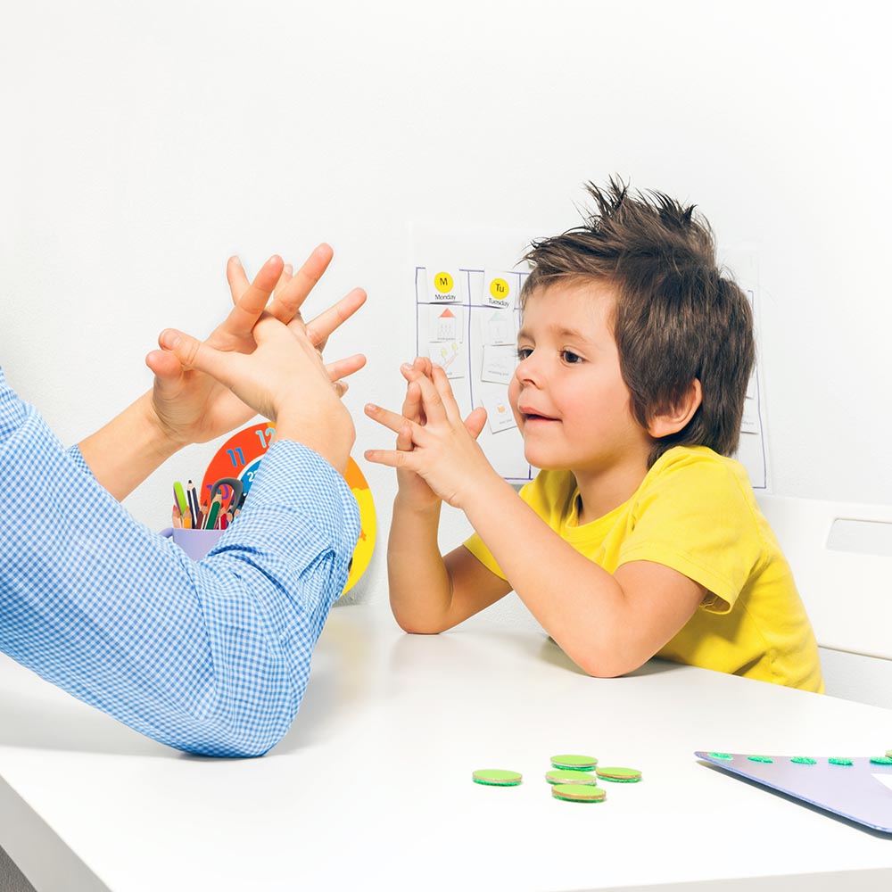 Boy exercises putting fingers with therapist