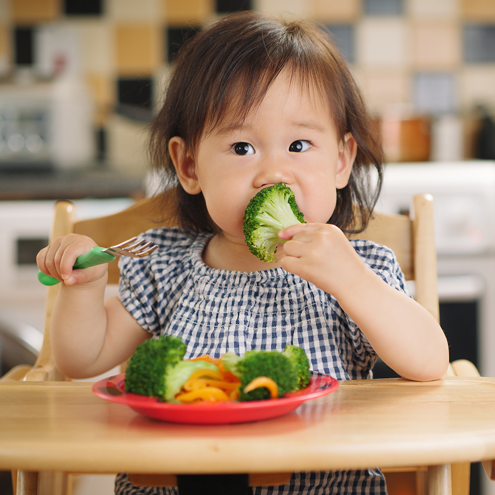 baby girl eating vegetable at home